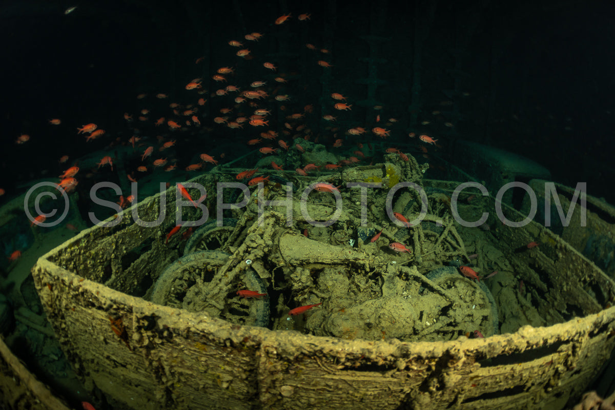 A diver is exploring a shipwreck in the Red Sea- using a rebreather to observe the preserved motorcycle resting on the ocean floor.