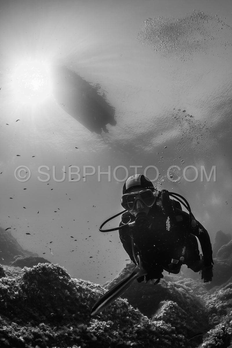 woman scuba diving over rocks in the Mediterranean Sea