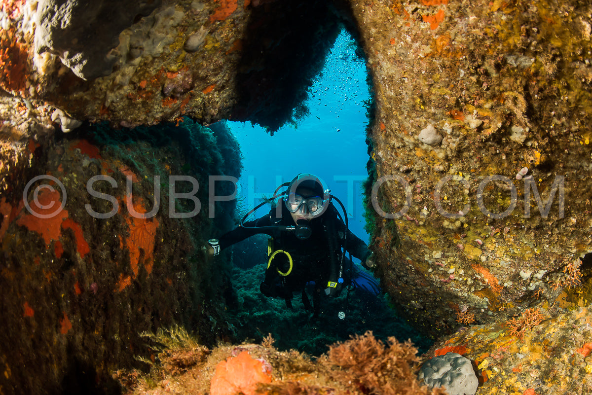 woman scuba diving over rocks in the Mediterranean Sea