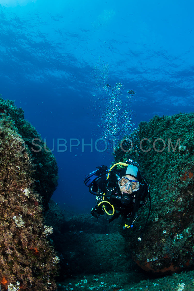 woman scuba diving over rocks in the Mediterranean Sea