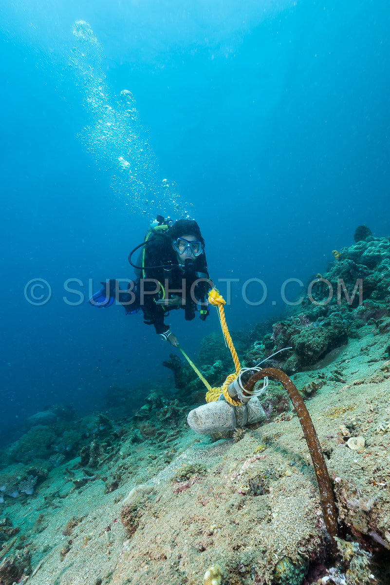 woman diver kolding a rope for safety decompression in strong current