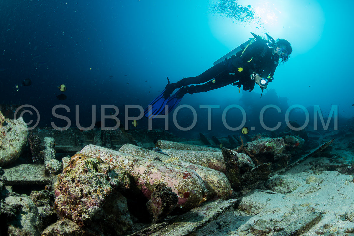 scuba diver over the wooden wreck of a diving boat with tanks in Maratua