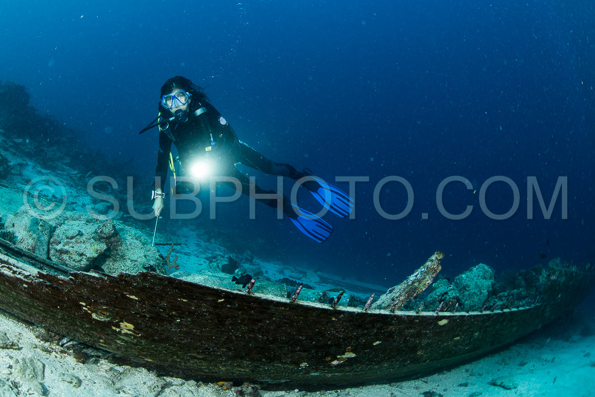 scuba diver over the wooden wreck of a diving boat with tanks in Maratua