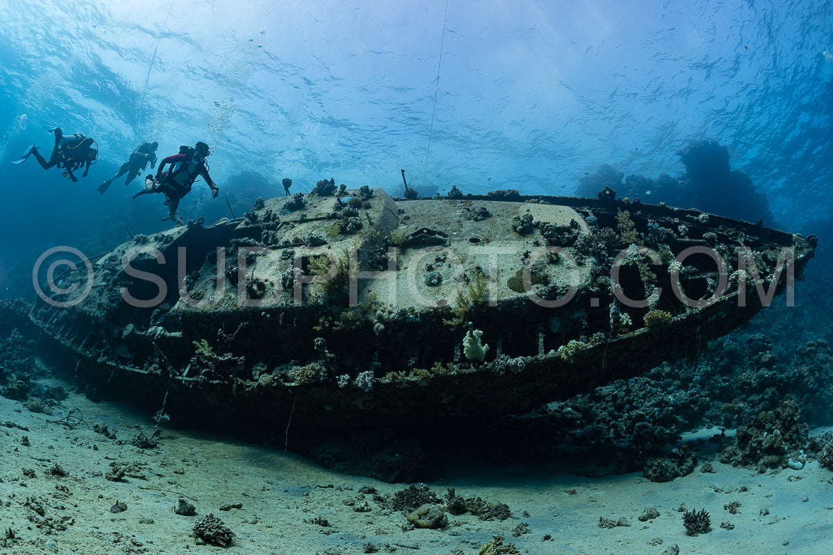 divers visiting an underwater wreck of a metal sailboat on a reef in the Rea Sea- Egypt