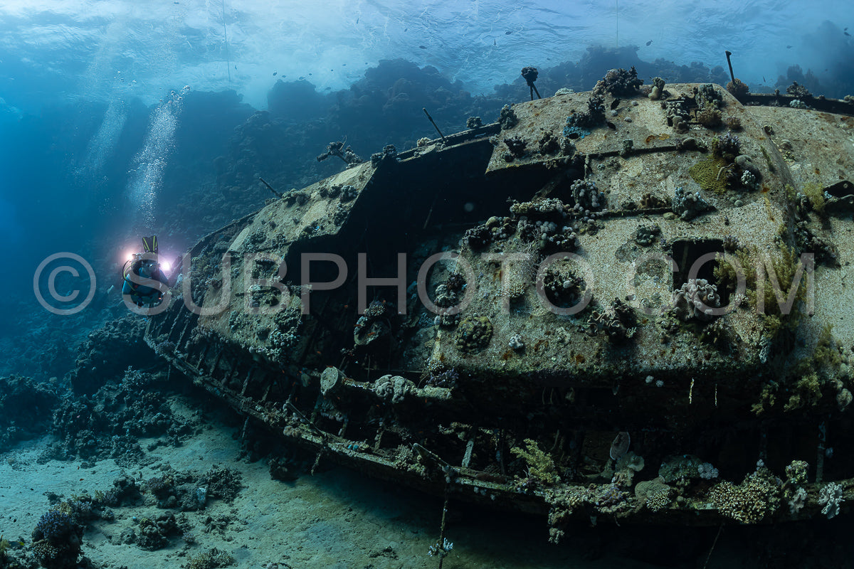 divers visiting an underwater wreck of a metal sailboat on a reef in the Rea Sea- Egypt