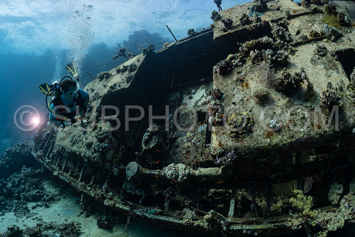 woman diver visiting an underwater wreck of a metal sailboat on a reef in the Rea Sea- Egypt