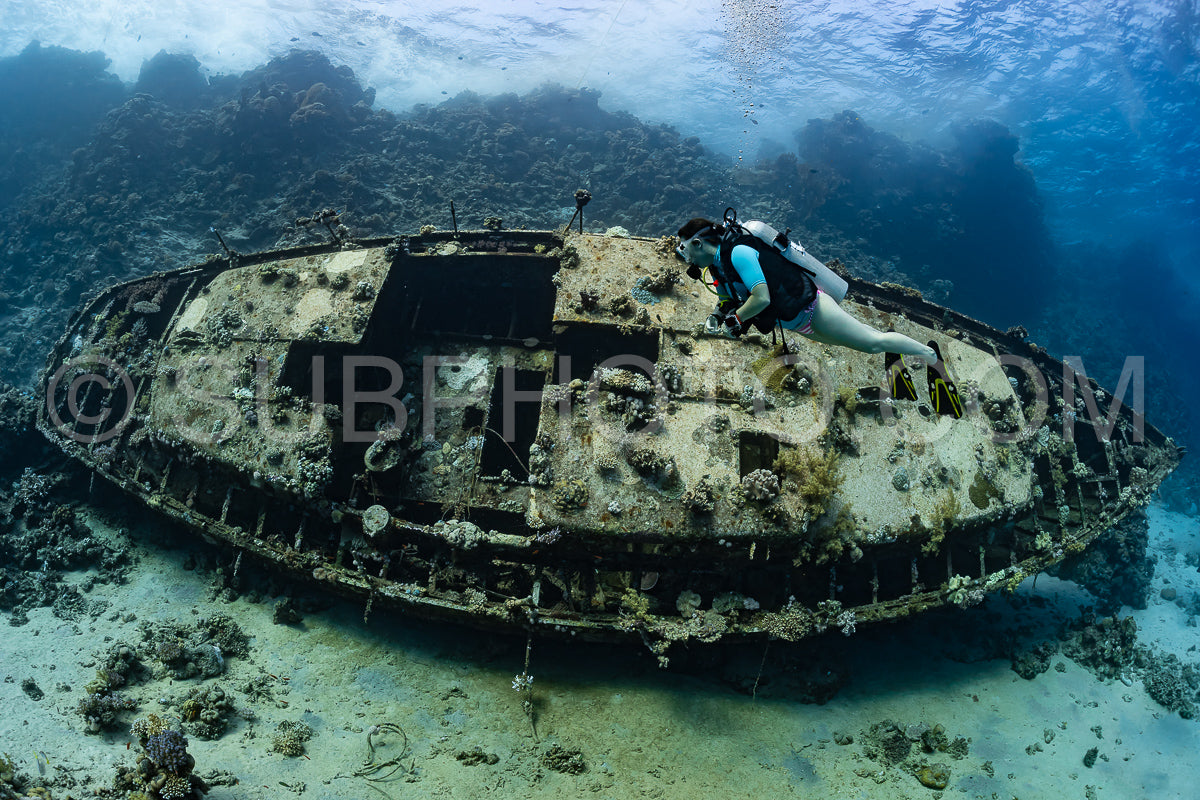 woman diver visiting an underwater wreck of a metal sailboat on a reef in the Rea Sea- Egypt