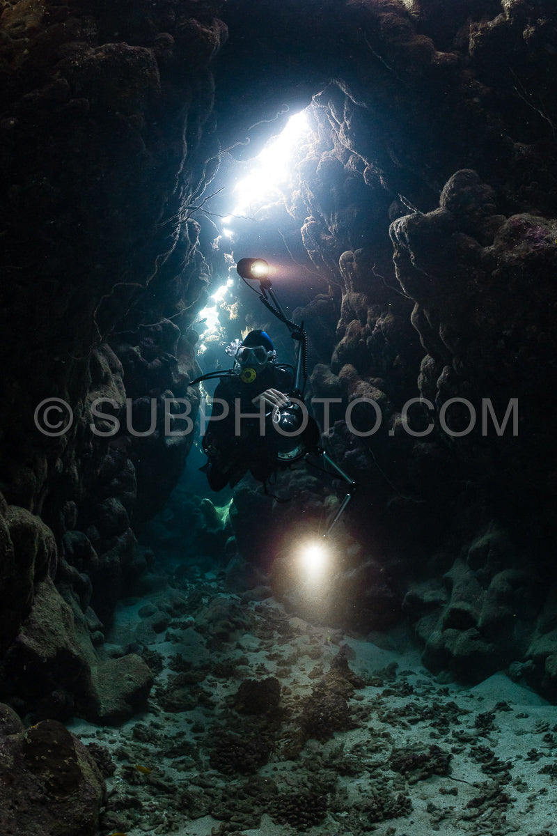 typical underwater cave in a red sea reef with an underwater photographer diver