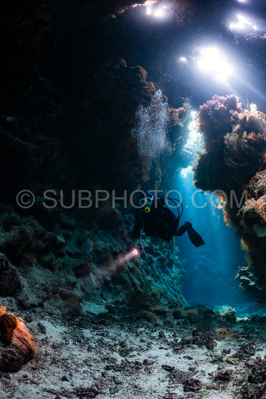 Photo de grotte sous-marine typique dans un récif de mer rouge avec un plongeur photographe sous-marin