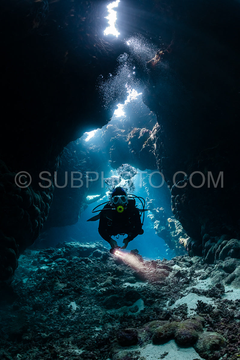 typical underwater cave in a red sea reef with an underwater photographer diver
