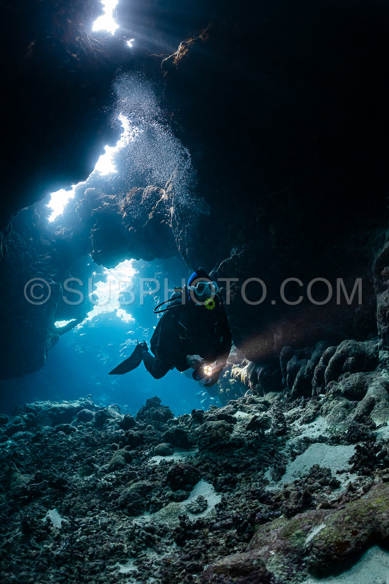 typical underwater cave in a red sea reef with an underwater photographer diver