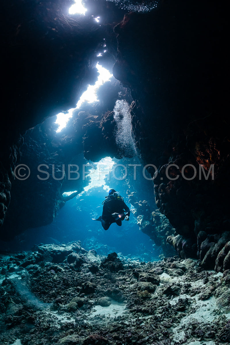 typical underwater cave in a red sea reef with an underwater photographer diver