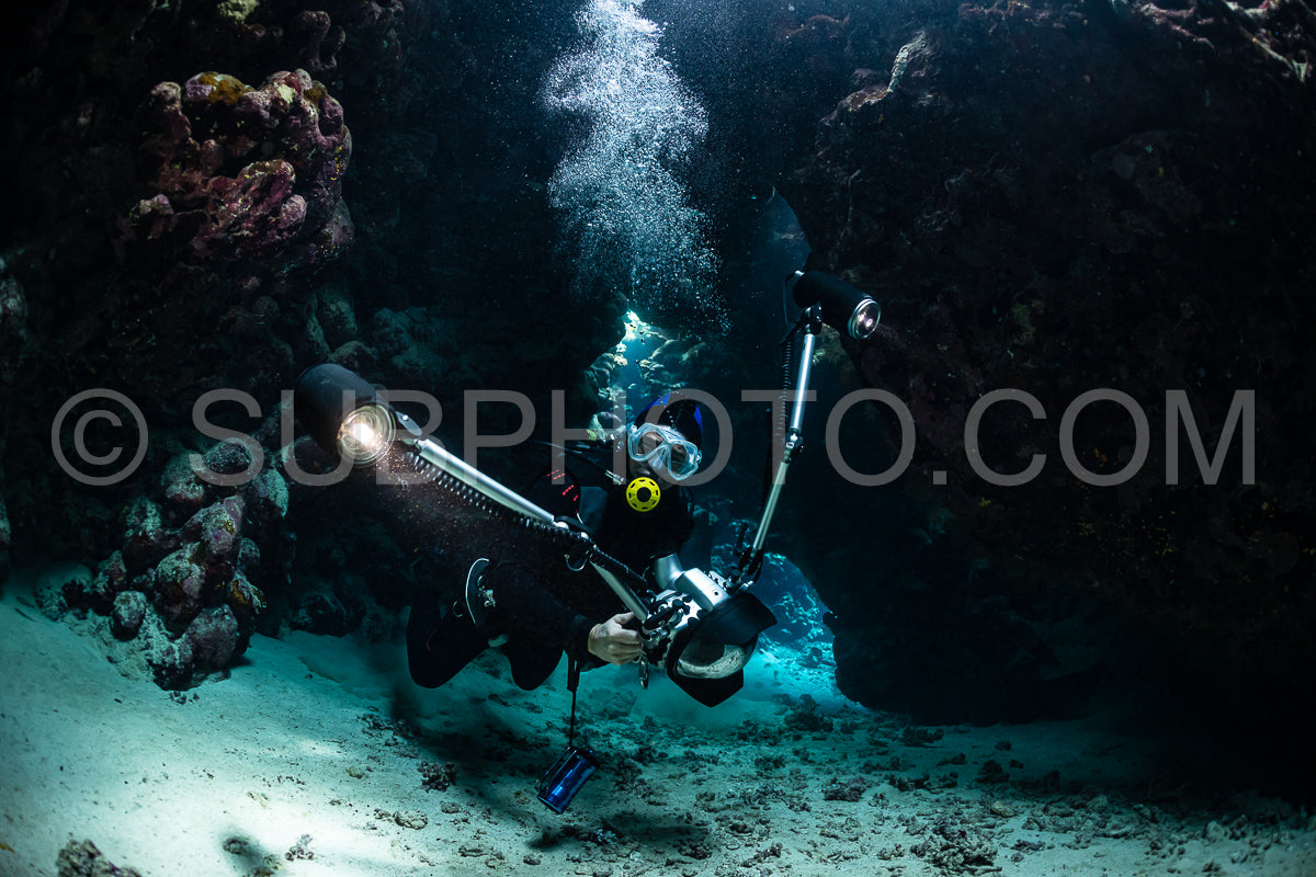Photo de grotte sous-marine typique dans un récif de mer rouge avec un plongeur photographe sous-marin