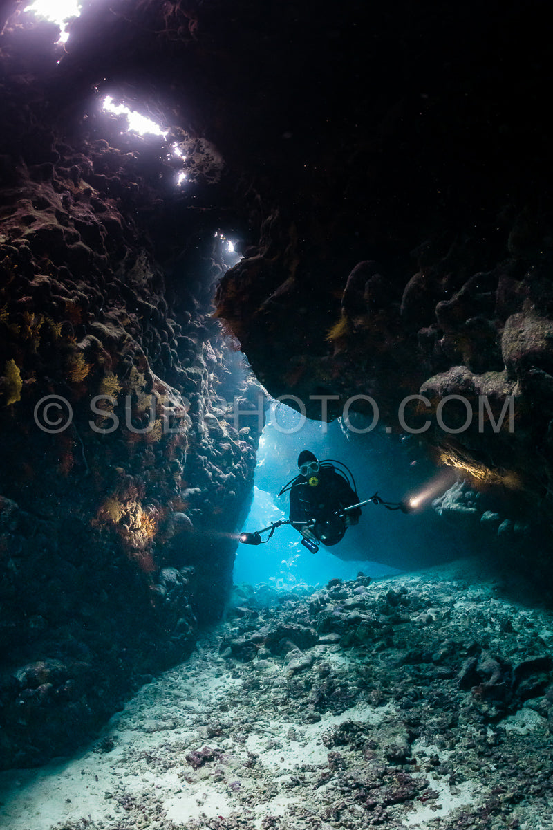 typical underwater cave in a red sea reef with an underwater photographer diver