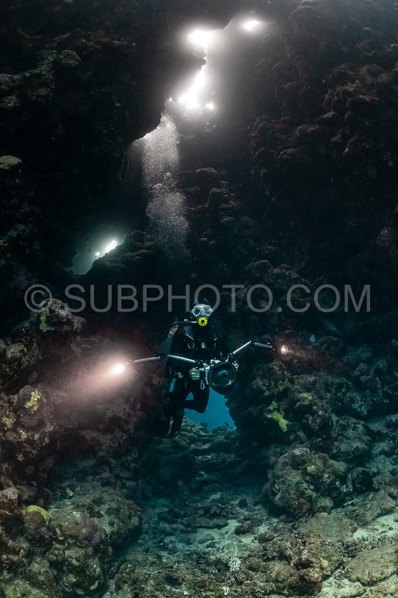typical underwater cave in a red sea reef with an underwater photographer diver