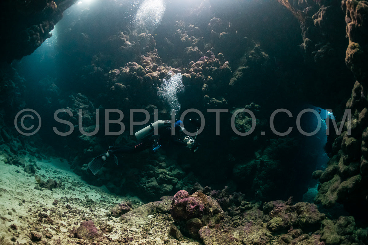 Photo de grotte sous-marine typique dans un récif de mer rouge avec un plongeur photographe sous-marin