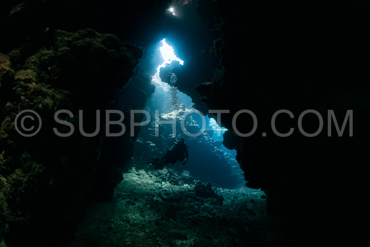Photo de grotte sous-marine typique dans un récif de mer rouge avec un plongeur photographe sous-marin