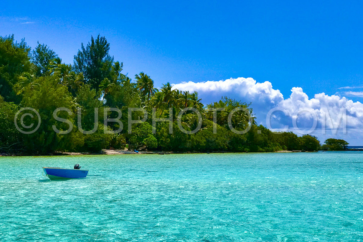 small blue boat close to Moorea motu in shallow water
