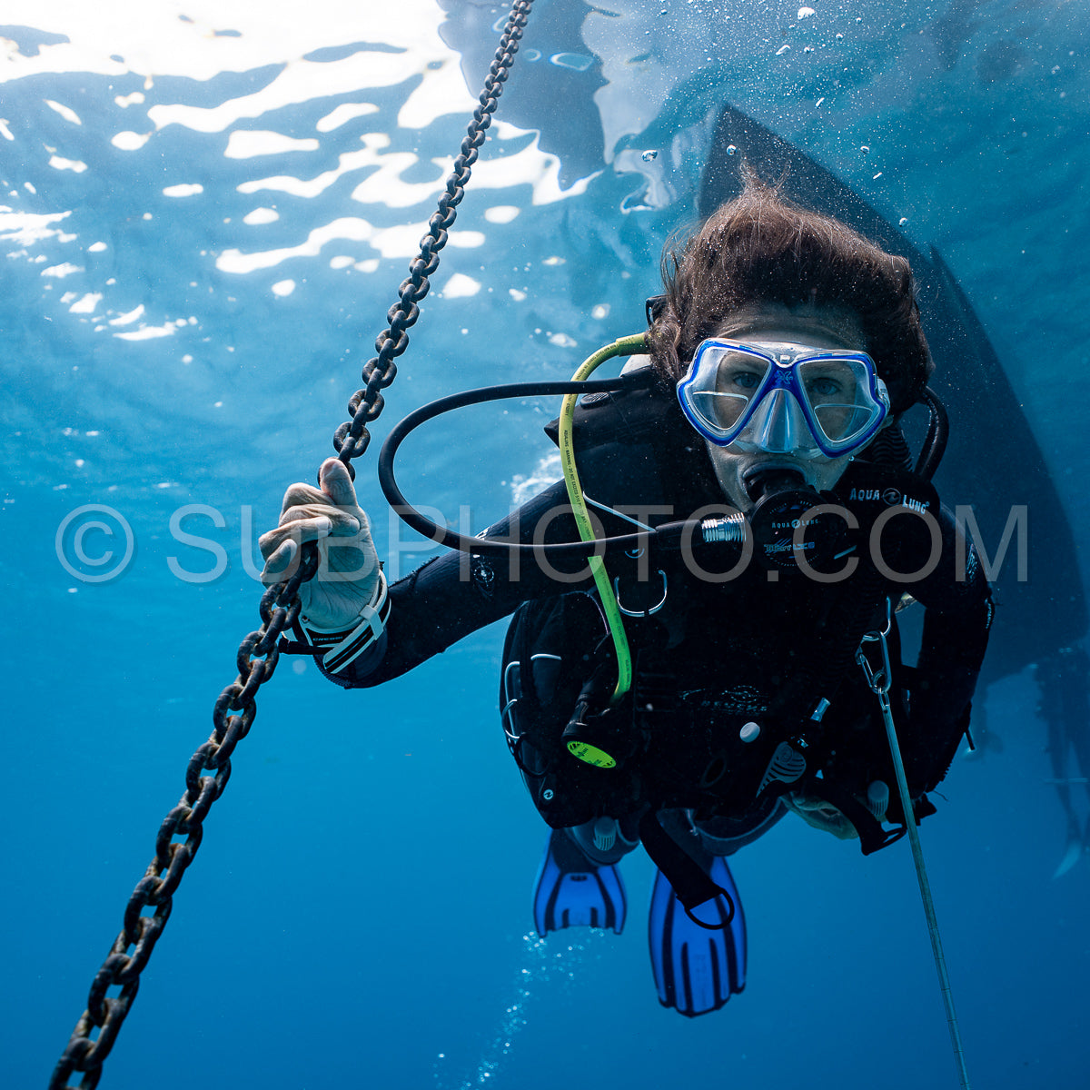 woman scuba diving at safety stop under the boat