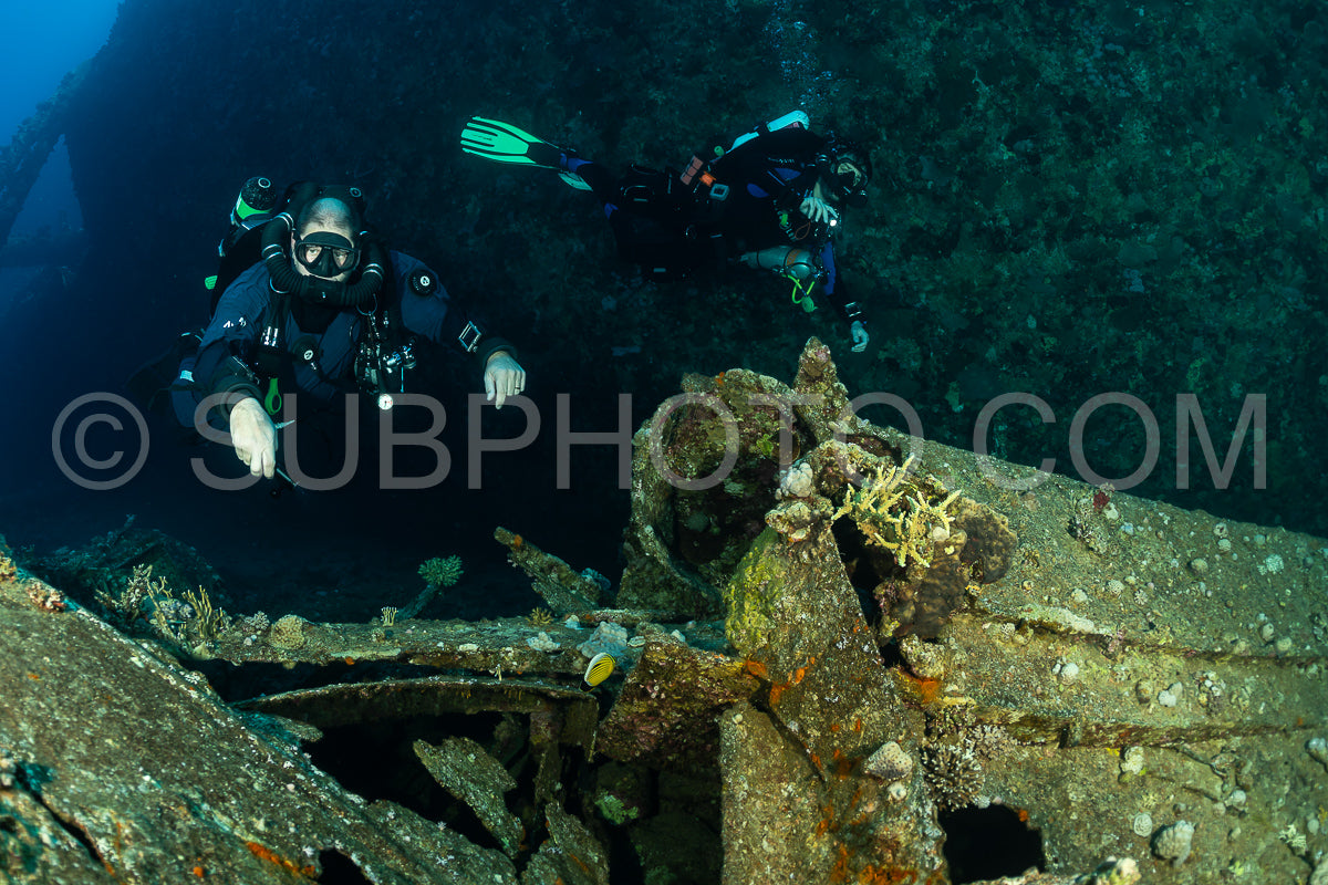 Two divers explore a shipwreck in the Red Sea. One diver is using a rebreather and is in the foreground- while the other diver is in the background.