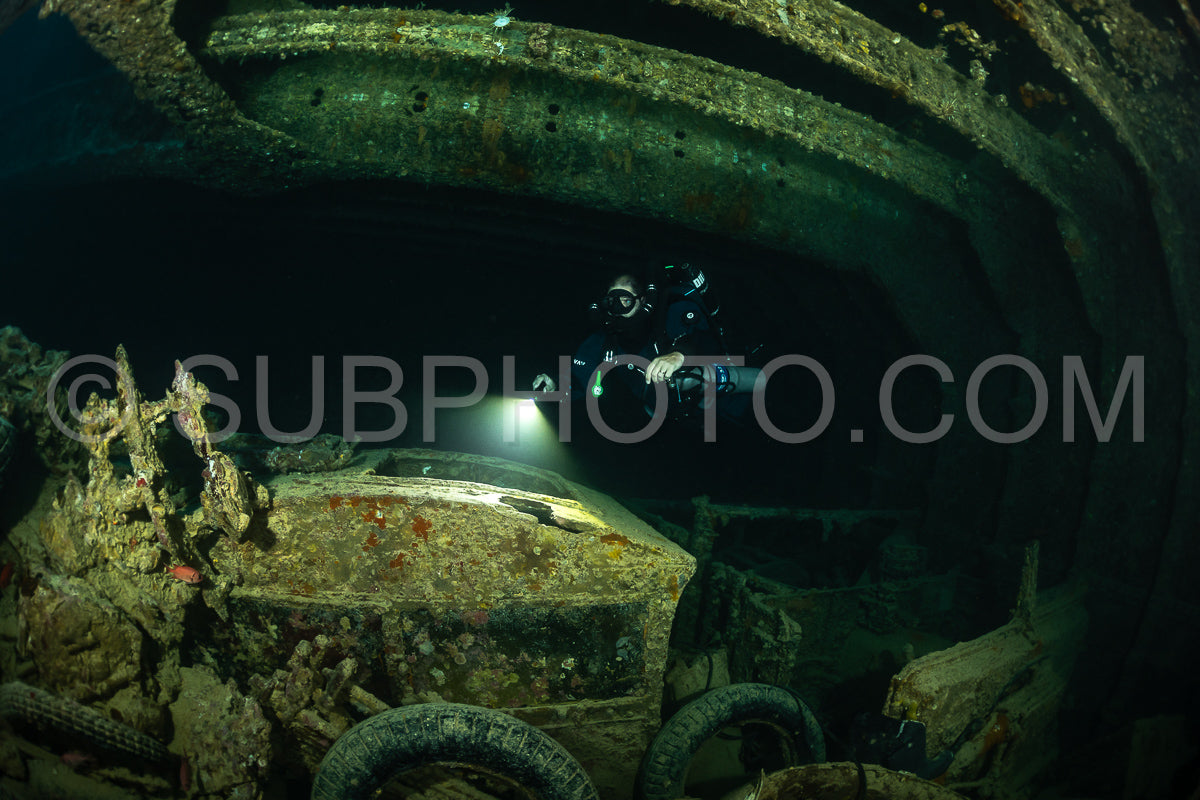 A diver wearing a rebreather swims through a dark- narrow passageway inside a shipwreck in the Red Sea.