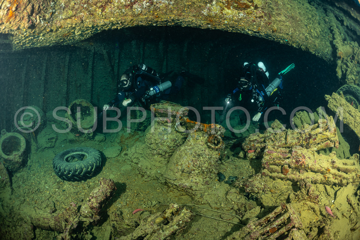 Two divers in full scuba gear explore the interior of a sunken ship in the Red Sea. They are using rebreathers- which allow them to stay underwater for longer periods of time.