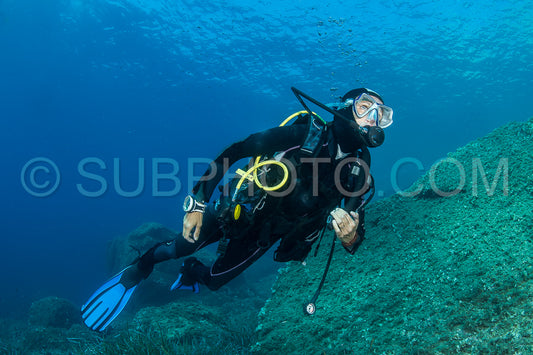woman scuba diving over rocks in the Mediterranean Sea