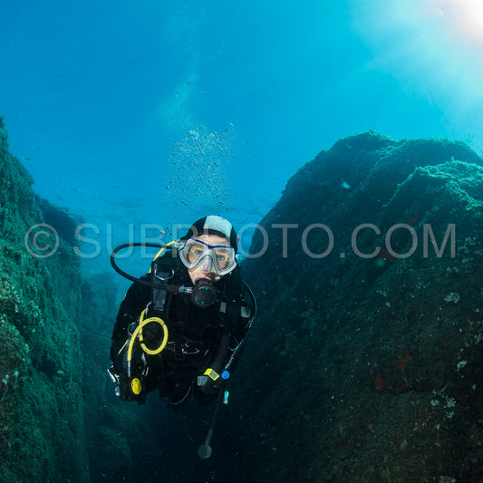 woman scuba diving over rocks in the Mediterranean Sea