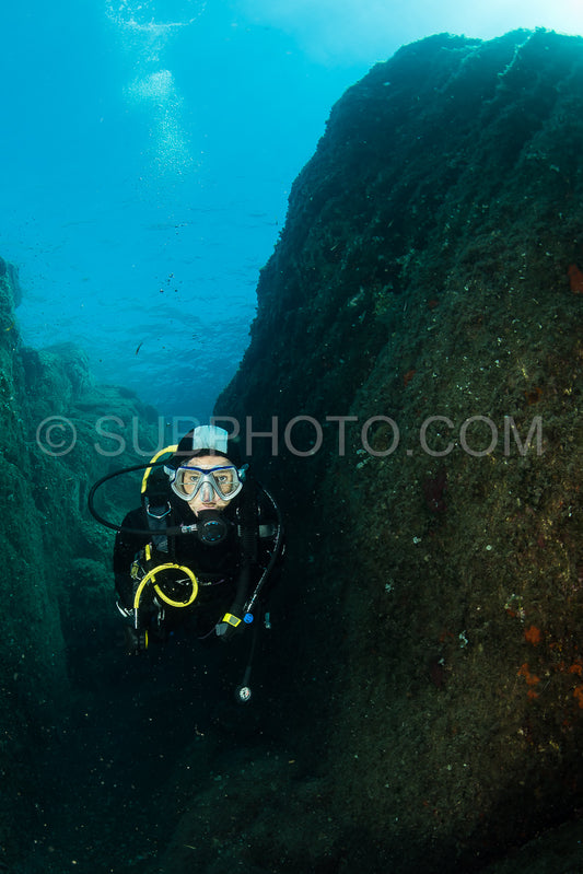 woman scuba diving over rocks in the Mediterranean Sea