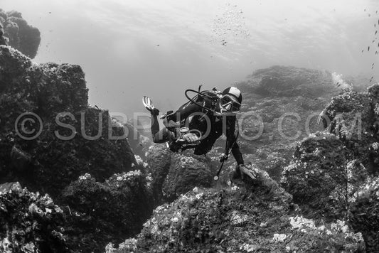 woman scuba diving over rocks in the Mediterranean Sea
