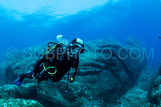 woman scuba diving over rocks in the Mediterranean Sea