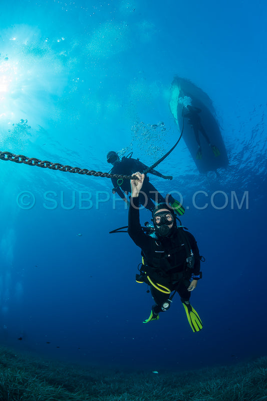 Divers making a decompression stop under their diving boat