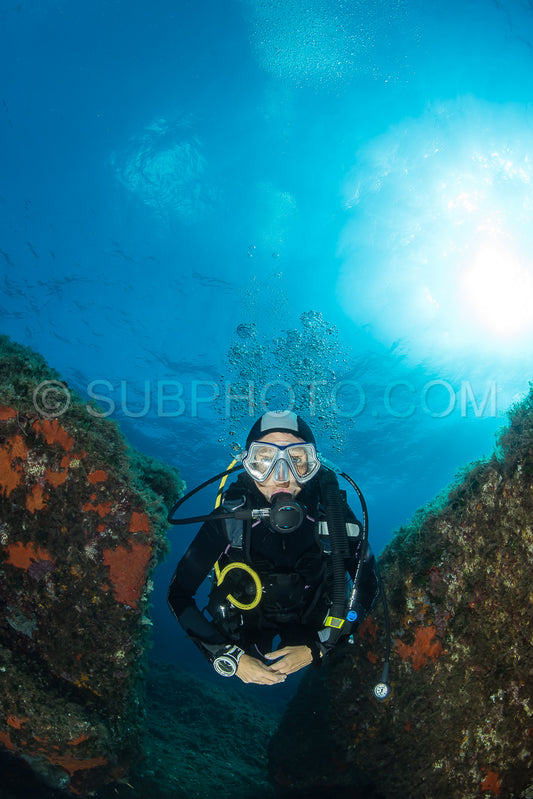 woman scuba diving over rocks in the Mediterranean Sea