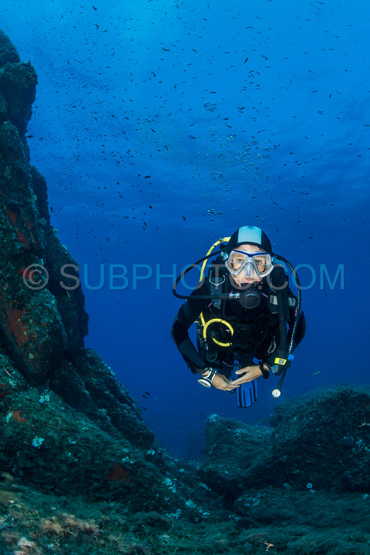 woman scuba diving over rocks in the Mediterranean Sea