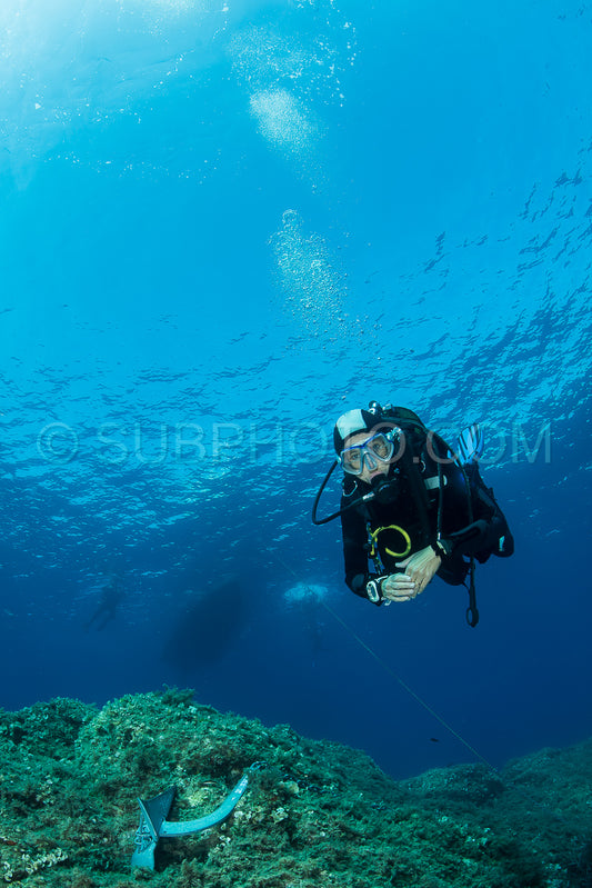 woman scuba diving over rocks in the Mediterranean Sea