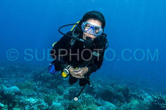 woman diver underwater over a colorful tropical reef with sea fan- coral and sponge in Rajat Ampat- Indonesia