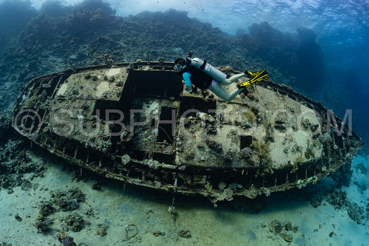 woman diver visiting an underwater wreck of a metal sailboat on a reef in the Rea Sea- Egypt