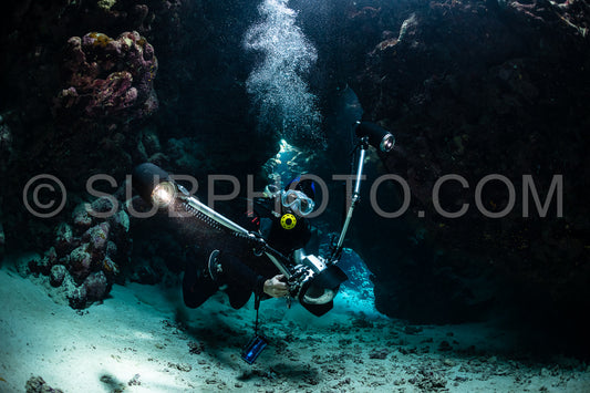 typical underwater cave in a red sea reef with an underwater photographer diver