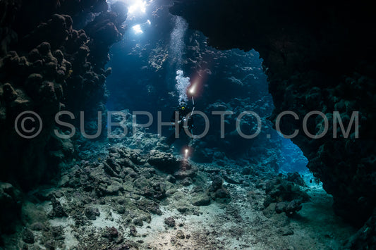 typical underwater cave in a red sea reef with an underwater photographer diver