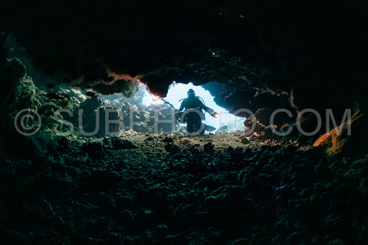 typical underwater cave in a red sea reef with an underwater photographer diver
