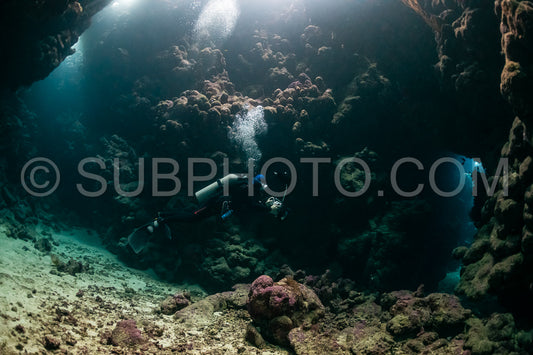 typical underwater cave in a red sea reef with an underwater photographer diver