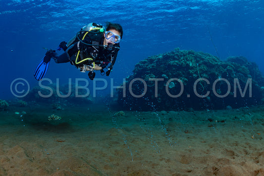 woman diver looking at gaz bubble coming from the volcano Pulau Sangeang