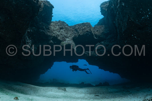woman diver visiting a cave under an arche
