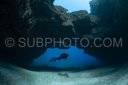 woman diver visiting a cave under an arche