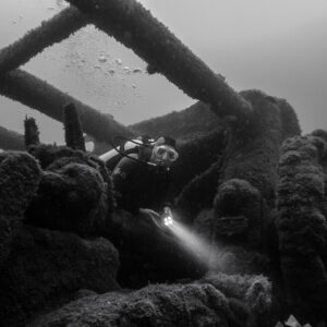 Black and white: diver with torch exploring among wreck girders, Ville de Rochefort wreck, Brittany, France