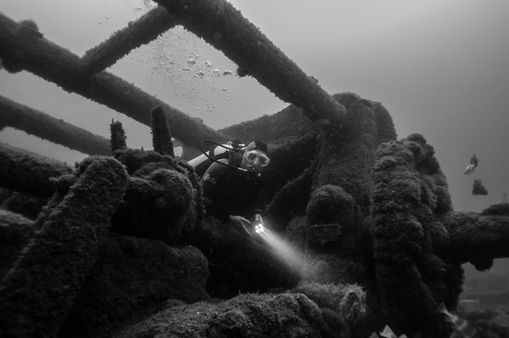 Black and white: diver with torch exploring among wreck girders, Ville de Rochefort wreck, Brittany, France