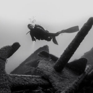 Black and white: diver above an anchor and scattered wreck debris, Ville de Rochefort wreck, Brittany, France