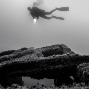 Black and white: diver hovering above a flat collapsed wreck section, Ville de Rochefort wreck, Brittany, France