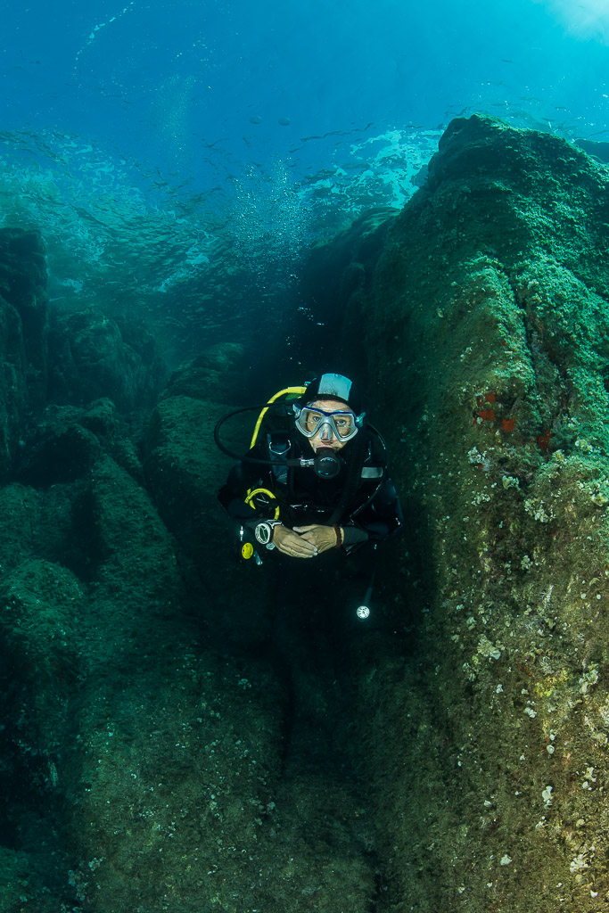 Woman diver in a green-tinted gully against a rock wall, Porto-Vecchio, Corsica, France