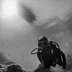 Black and white: woman diver with dive boat silhouette above, Porto-Vecchio, Corsica, France
